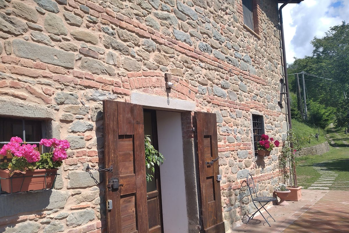 A stone building with a wooden door, potted plants, and a small outdoor seating area.