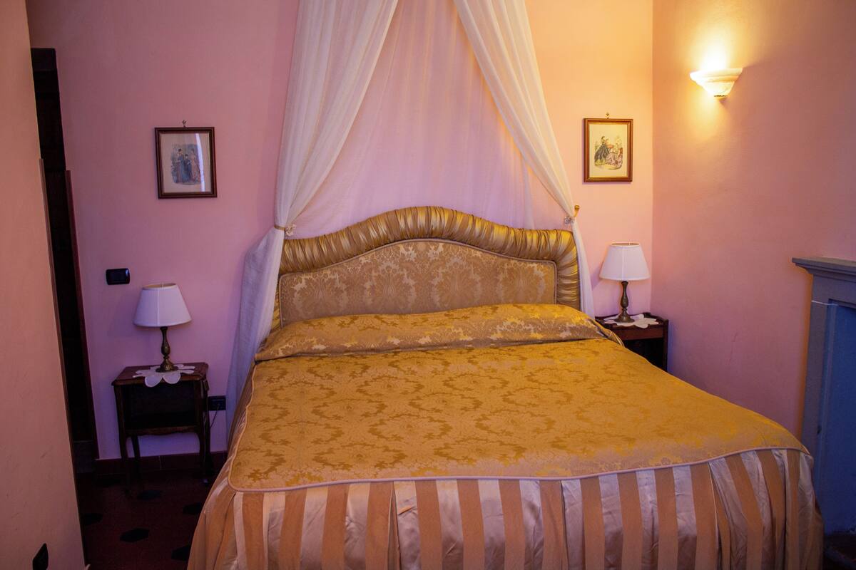 A bedroom with a bed, a nightstand, a lamp, and a picture on the wall.