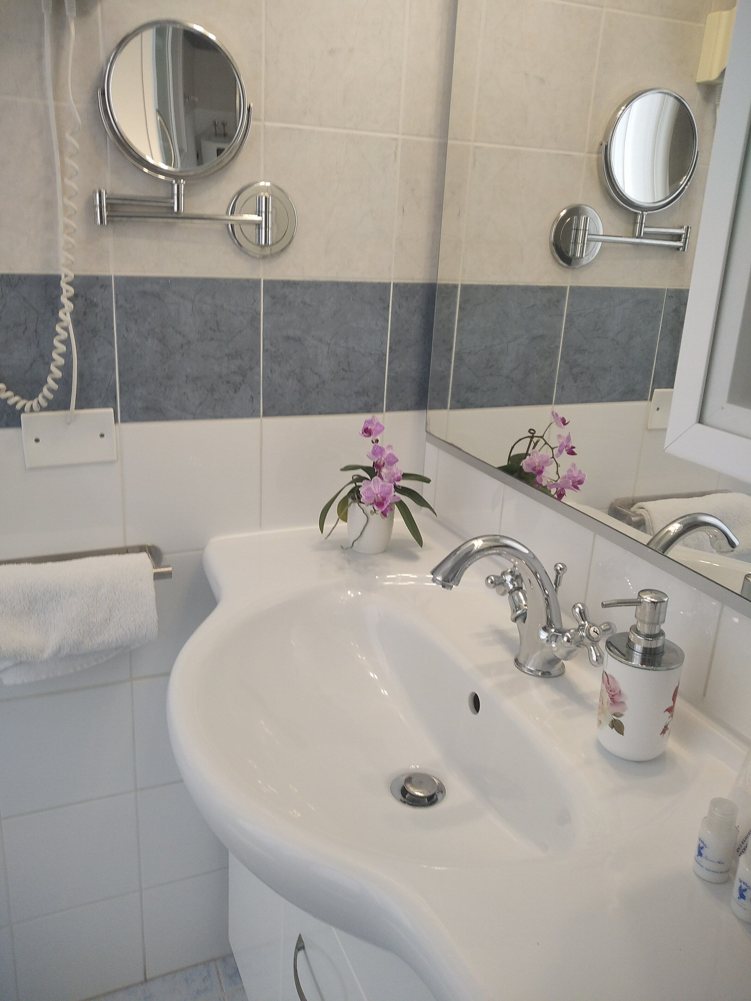 Een badkamer met een wit wastafel, een spiegel en een handdoekhouder.