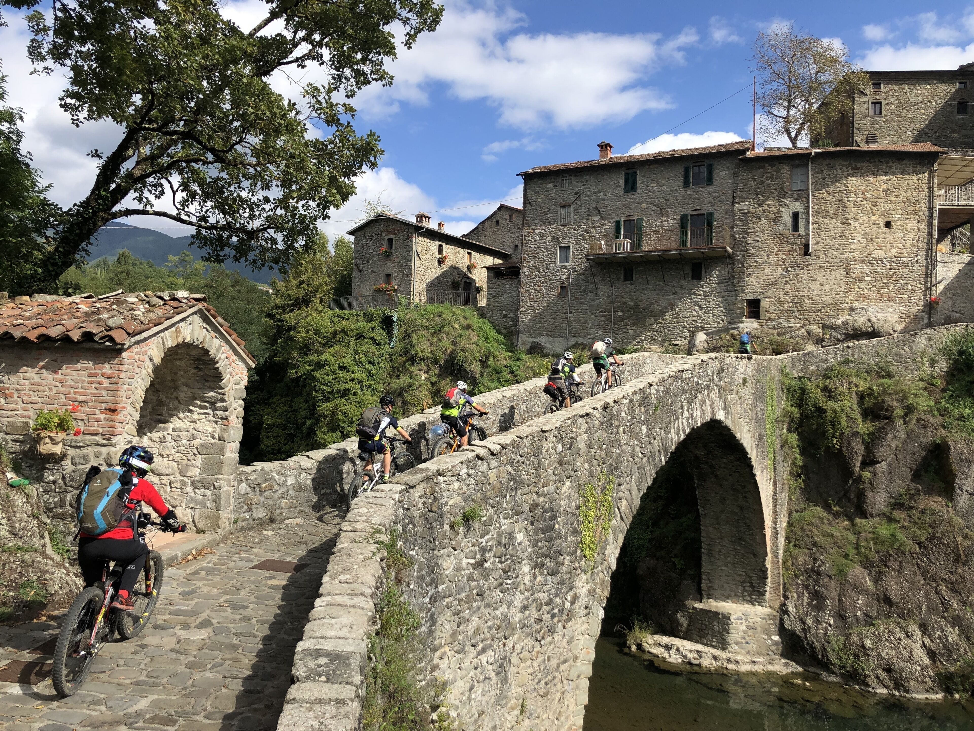 Un pont de pierre sur lequel des cyclistes circulent.