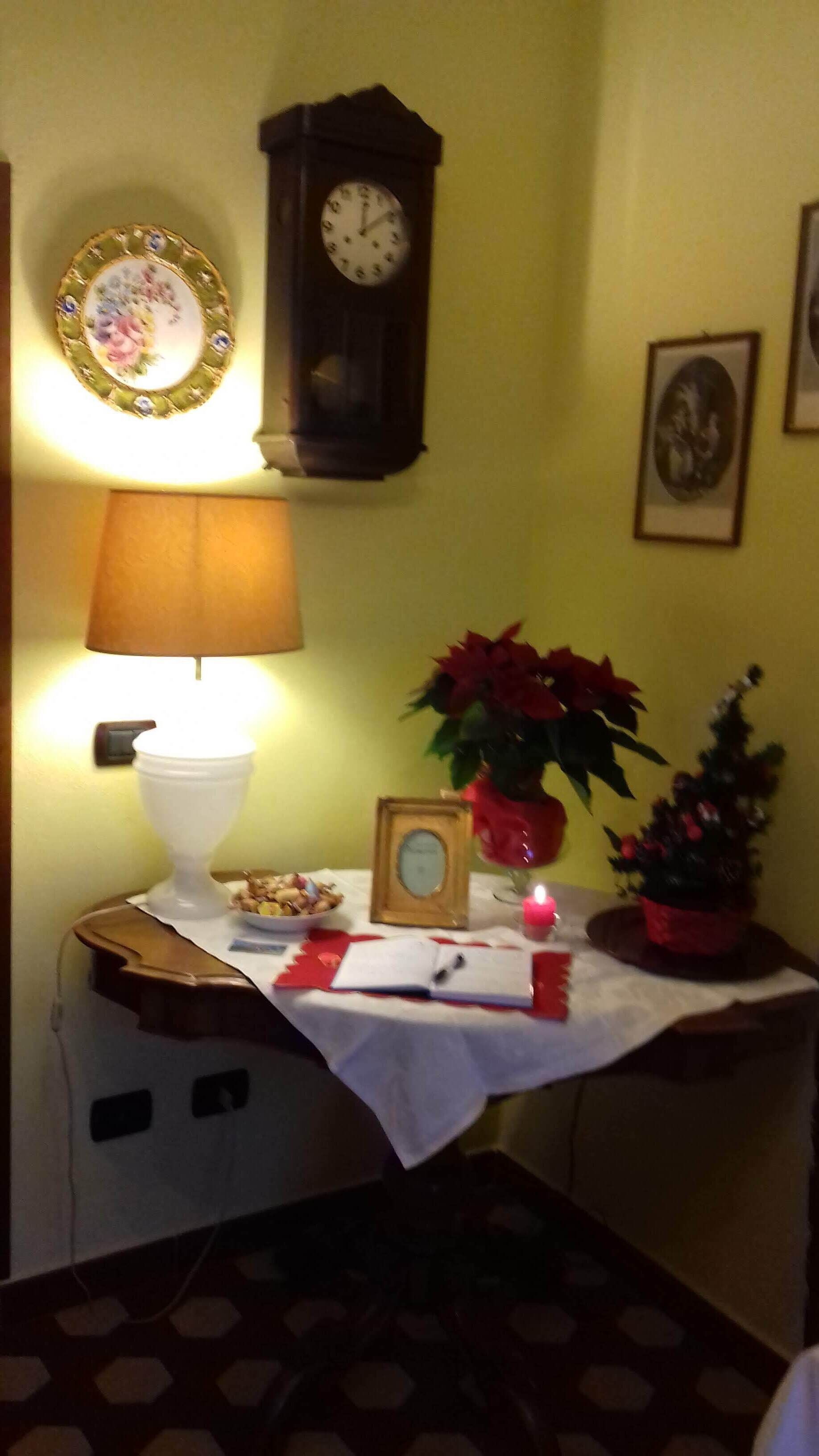 A small table with a clock, a lamp, and a potted plant.