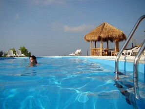 A swimming pool with clear blue water, lounge chairs, and a thatched-roof hut. - Acqua di Friso (Cropani)