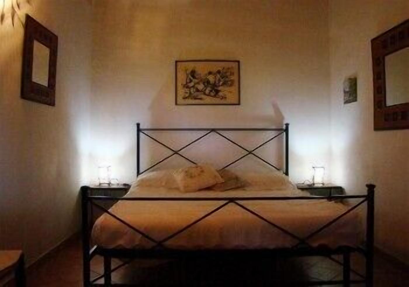A single bed with a cross-back design, two bedside tables, and a framed artwork above the bed.