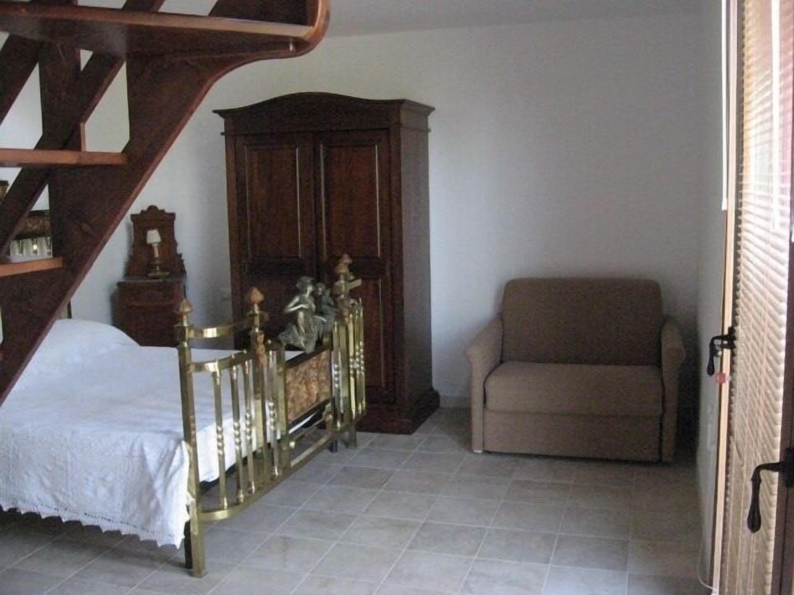 A bedroom with a bed, a wooden cabinet, and a sofa.