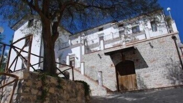 A stone building with a wooden door and a staircase leading up to it. - Puesta de Sol (Tramonti)