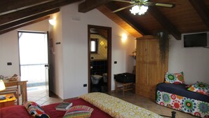 A bedroom with a bed, a wooden wardrobe, a bathroom with a toilet and sink, and a dining area with a table and chairs. - Puesta de Sol (Tramonti)