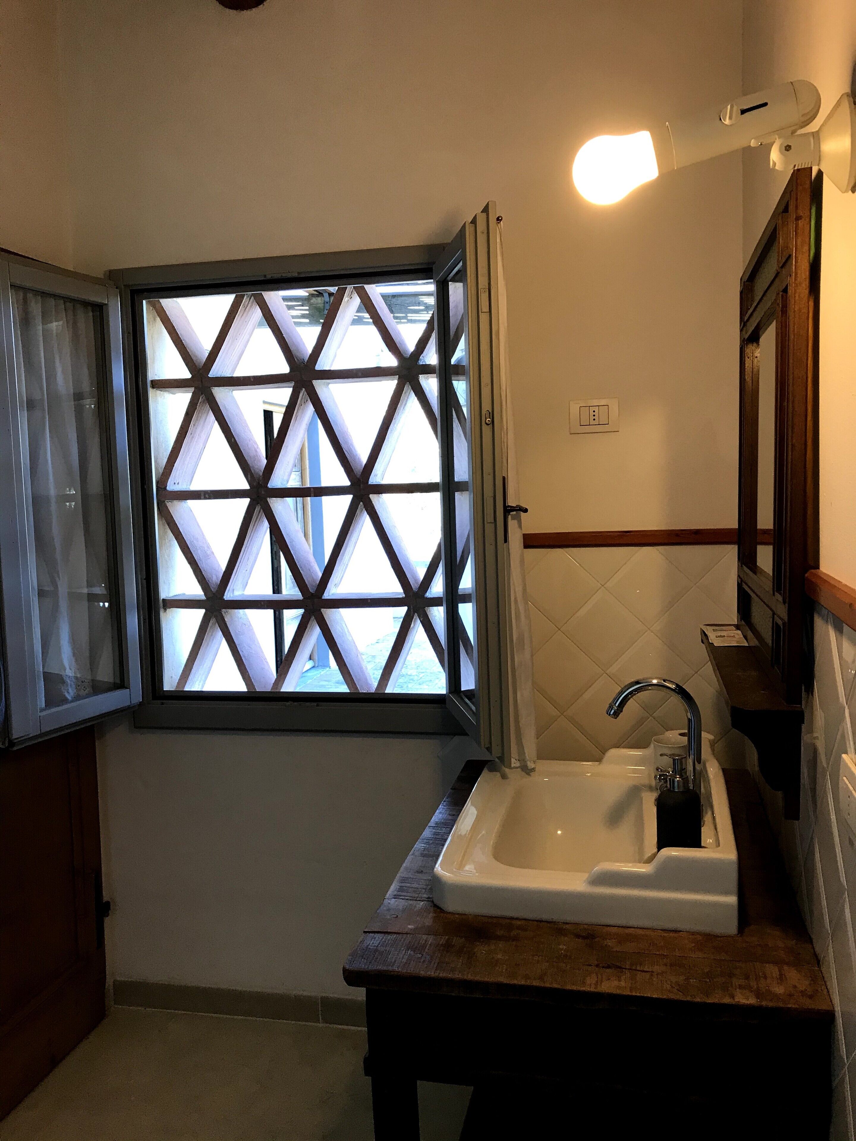 A bathroom with a window, sink, and mirror.