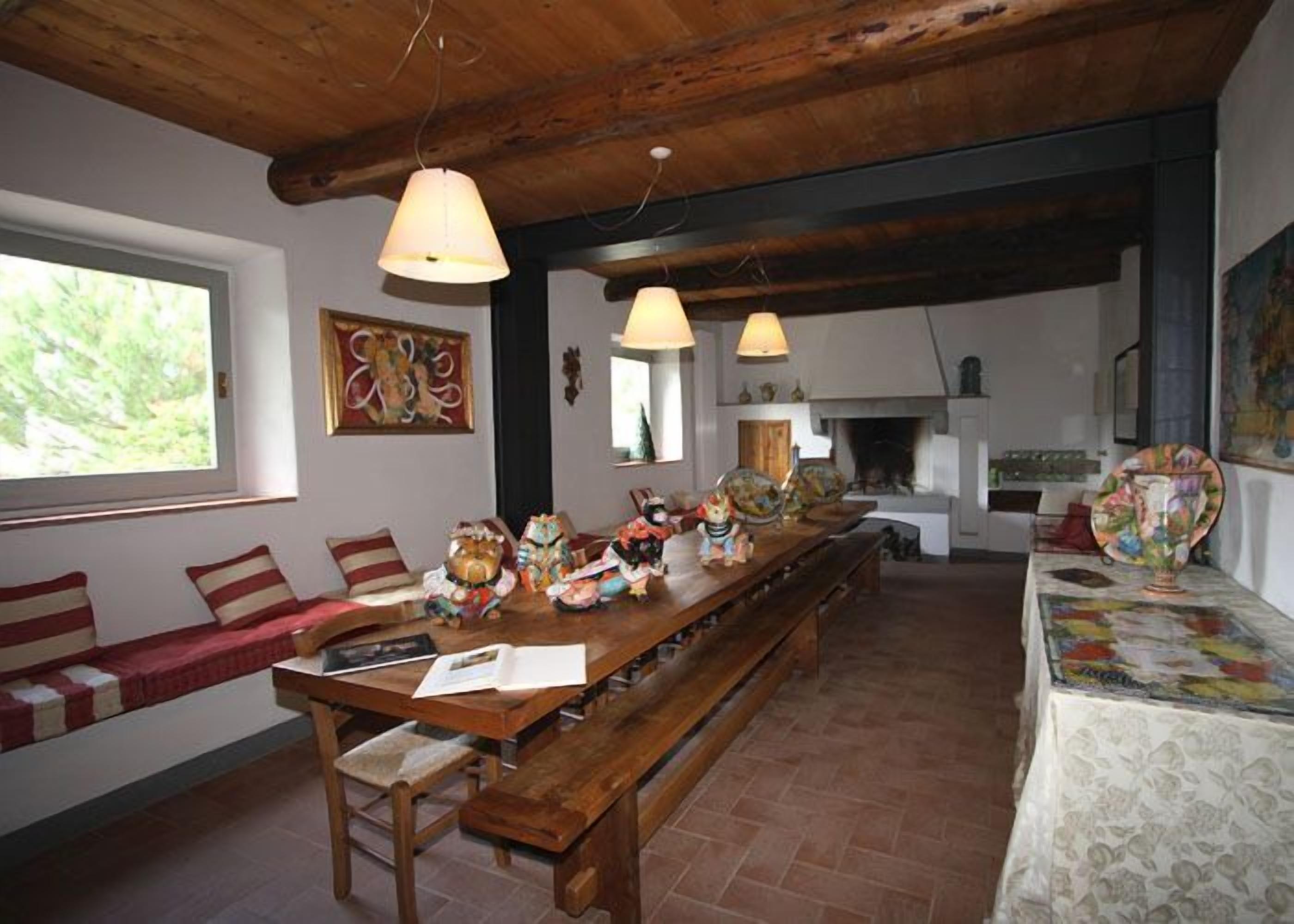 Un comedor rústico con una larga mesa de madera, bancos y lámparas colgantes.