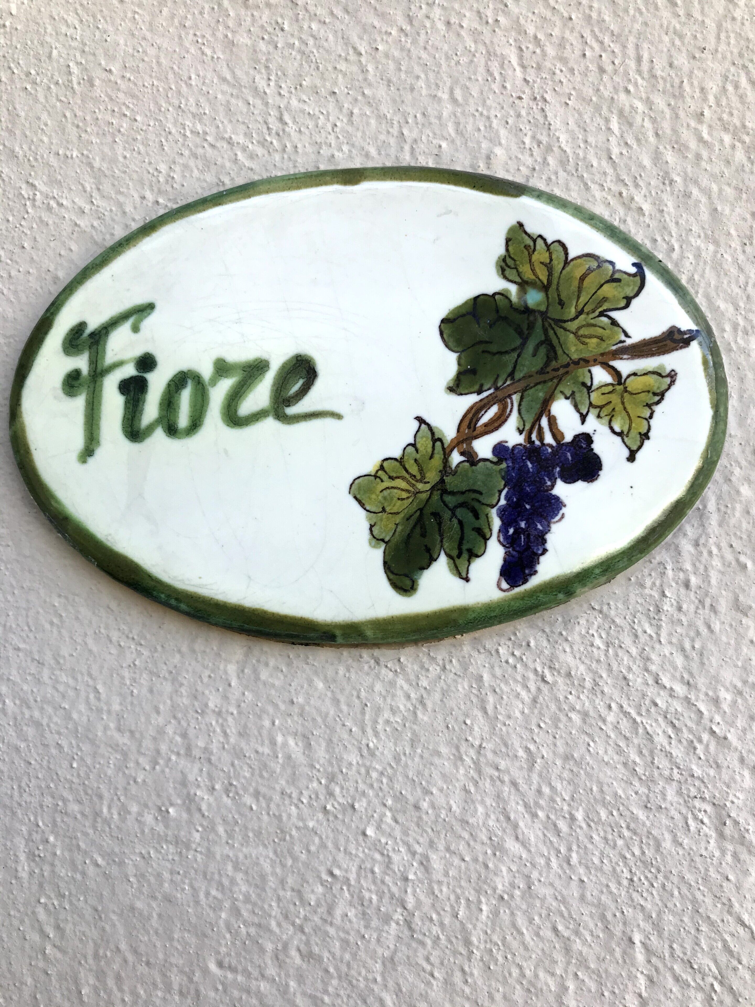 A ceramic tile with the word "Fiore" and a grapevine illustration.