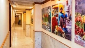 A hotel corridor with marble flooring and a wall adorned with floral artwork. - Hotel Alka Classic (New Delhi)