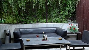 A modern outdoor seating area with a sofa, two armchairs, a coffee table, and a round ottoman. - Hotel Alka Classic (New Delhi)
