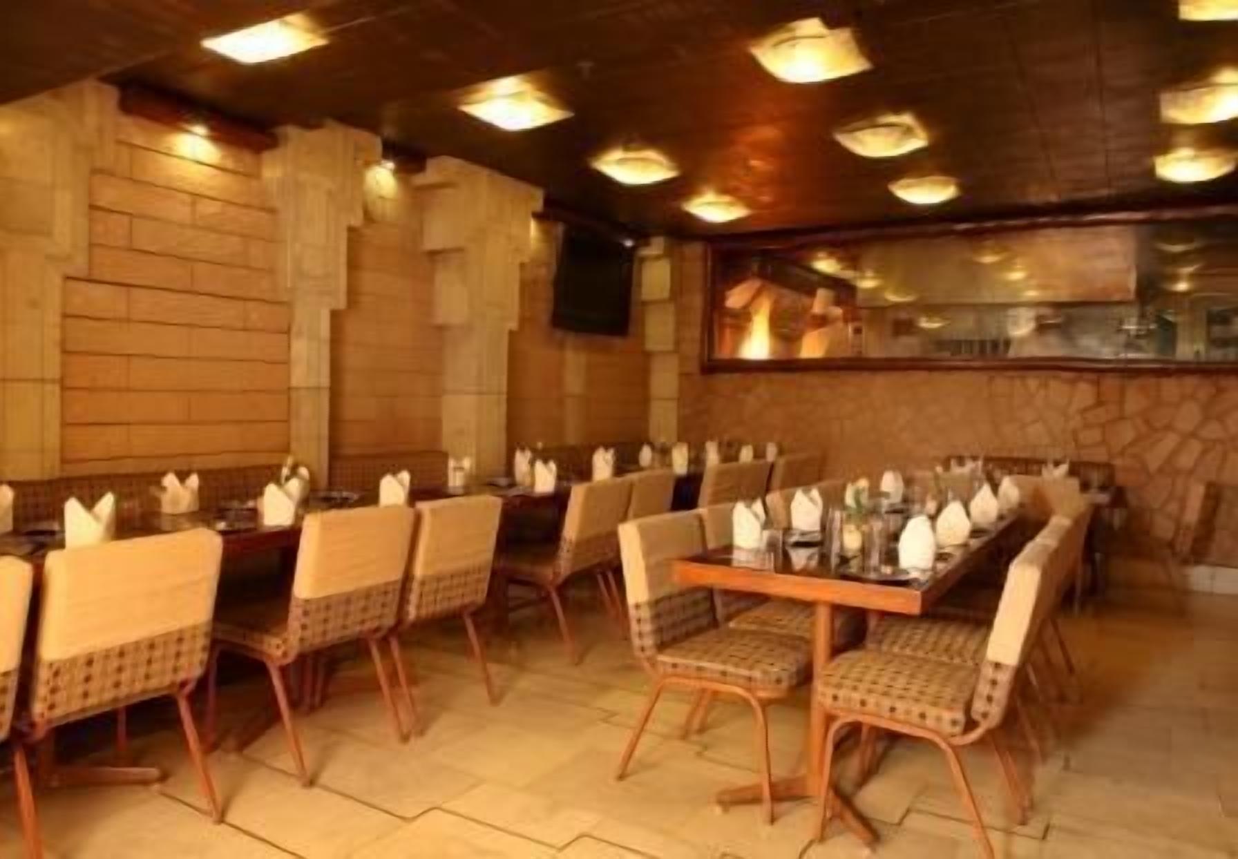 A restaurant with a long wooden table set for a meal, surrounded by wicker chairs.