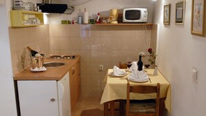 A compact kitchen with a refrigerator, microwave, and a dining table set for two with chairs. - Apartment Dubrovnik-Center (Dubrovnik)