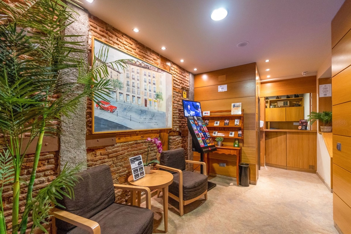 A cozy seating area with a brick wall, a large framed picture, and a small table with chairs.