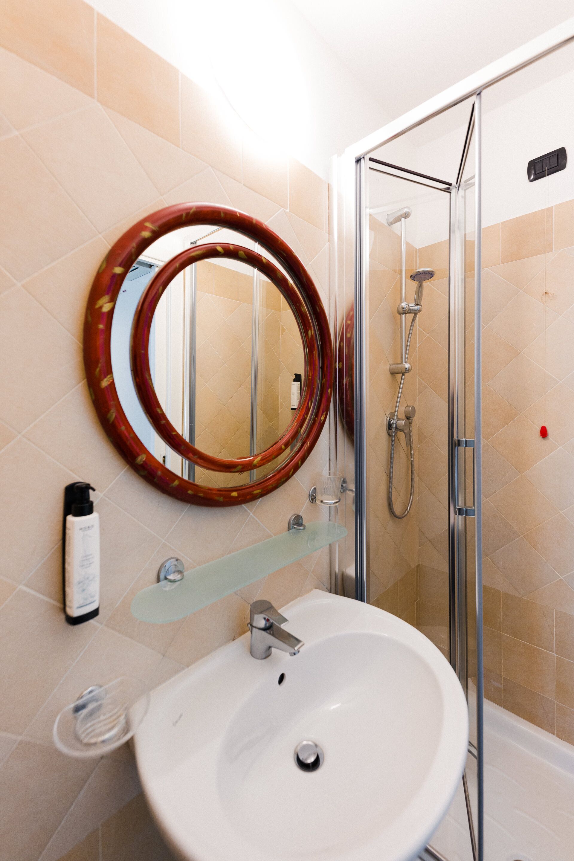 A bathroom with a white sink, a glass shower enclosure, and a mirror with a wooden frame.