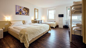 Habitación de hotel con dos camas, un escritorio, una silla, un televisor y un cuadro en la pared.