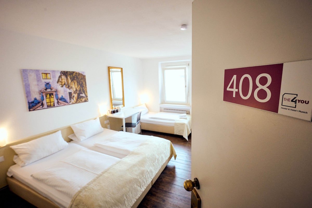 Ein Hotelzimmer mit zwei Betten, einem Schreibtisch, einem Spiegel und einem Bild an der Wand. Die Zimmernummer ist 408.