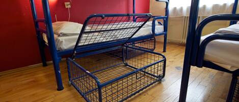 A bunk bed with a desk and chair, a lamp, and a window with curtains.
