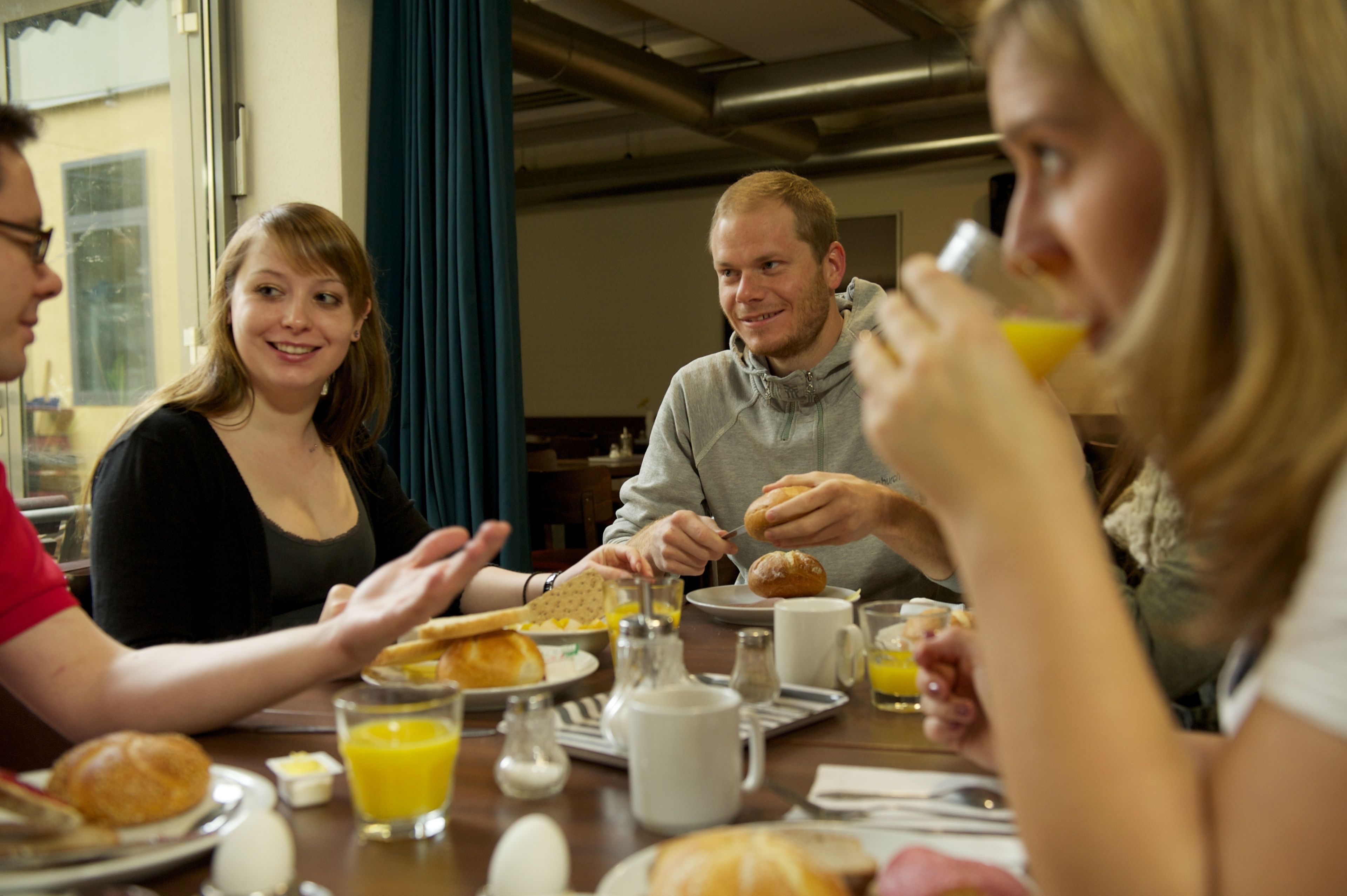 A group of people sitting around a table with breakfast items like eggs, toast, and juice.