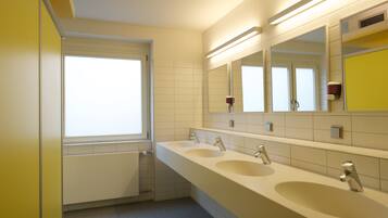 Ein modernes Badezimmer mit drei Waschbecken, einem großen Spiegel und einem Fenster.
