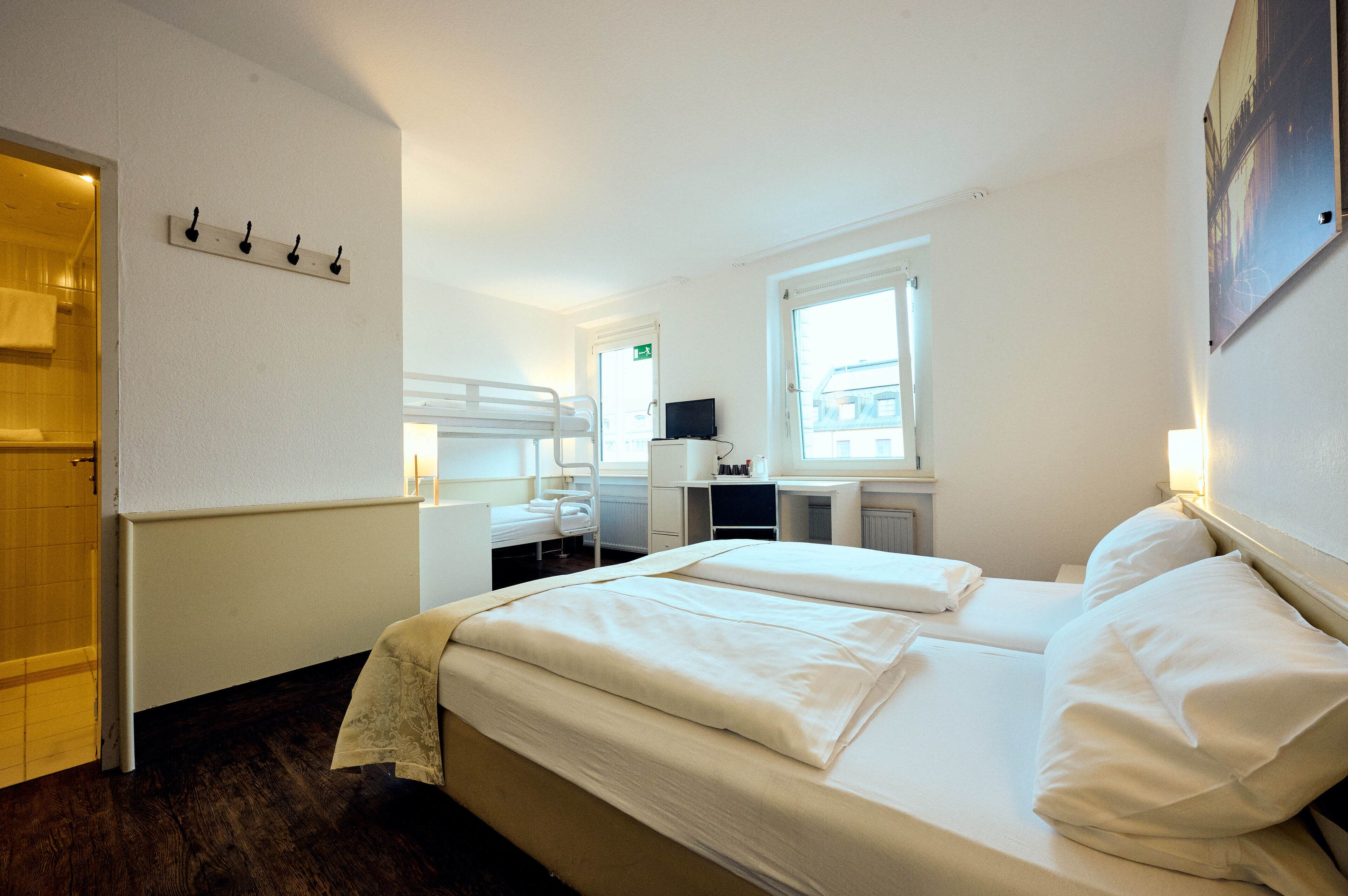 Hotellihuone, jossa on sänky, työpöytä, tuoli ja ikkuna.