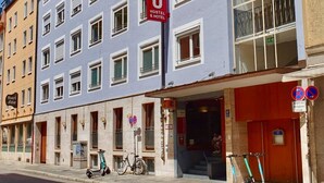 Un edificio de varios pisos con un cartel rojo que indica que es un albergue y un hotel.