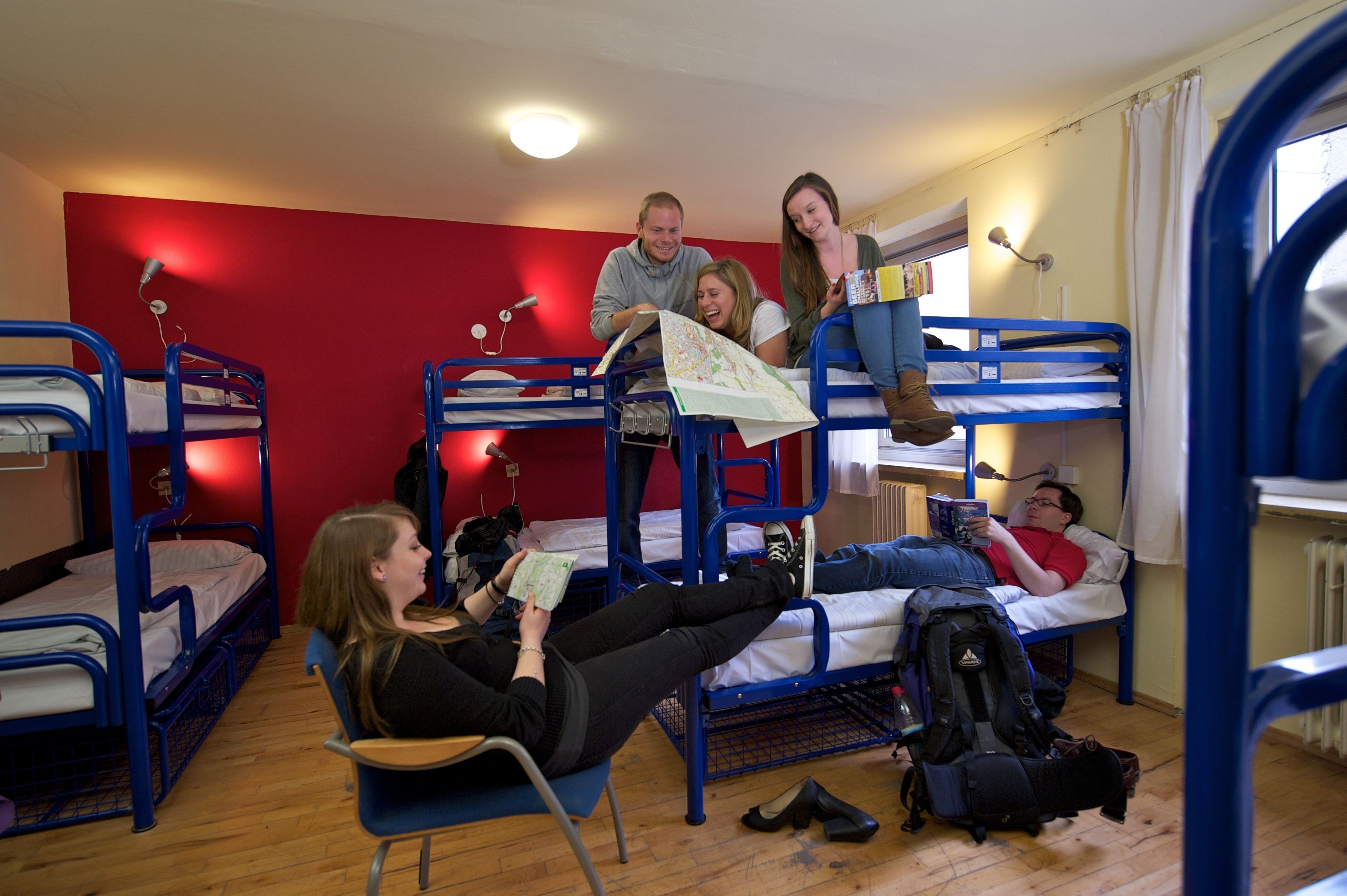 Un dormitorio con literas, una pared roja y una ventana.