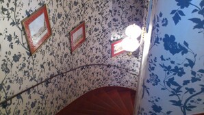 A spiral staircase with floral wallpaper and framed pictures on the walls. - Boutique Hotel Kugel Wien (Vienna)