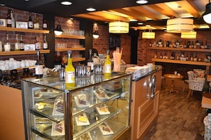 A bakery with a glass display case filled with pastries, shelves of baked goods, and a variety of bottles on the walls.