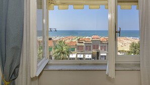 A view from a window overlooking a beach with buildings and palm trees. - Hotel La Pace (Viareggio)