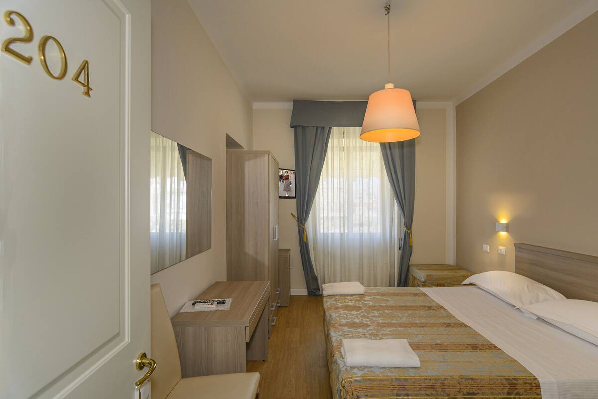 Ein Hotelzimmer mit Bett, Nachttisch, Lampe und Spiegel.