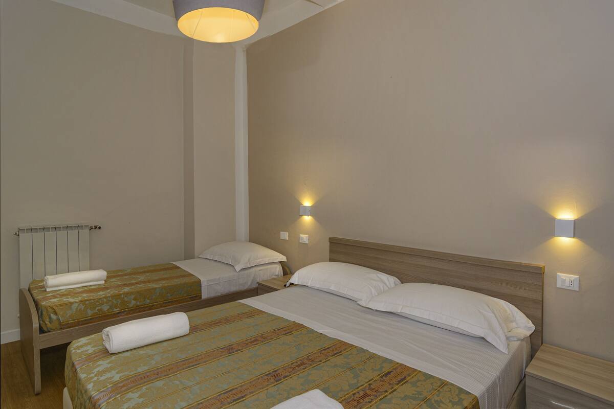 Ein Hotelzimmer mit zwei Einzelbetten, einem Holz-Kopfteil und zwei Wandleuchten.