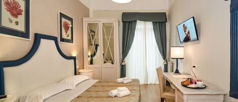 A hotel room with a bed, bedside table, desk, and a television.