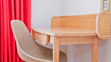 A wooden desk with a woven chair and a small table lamp.