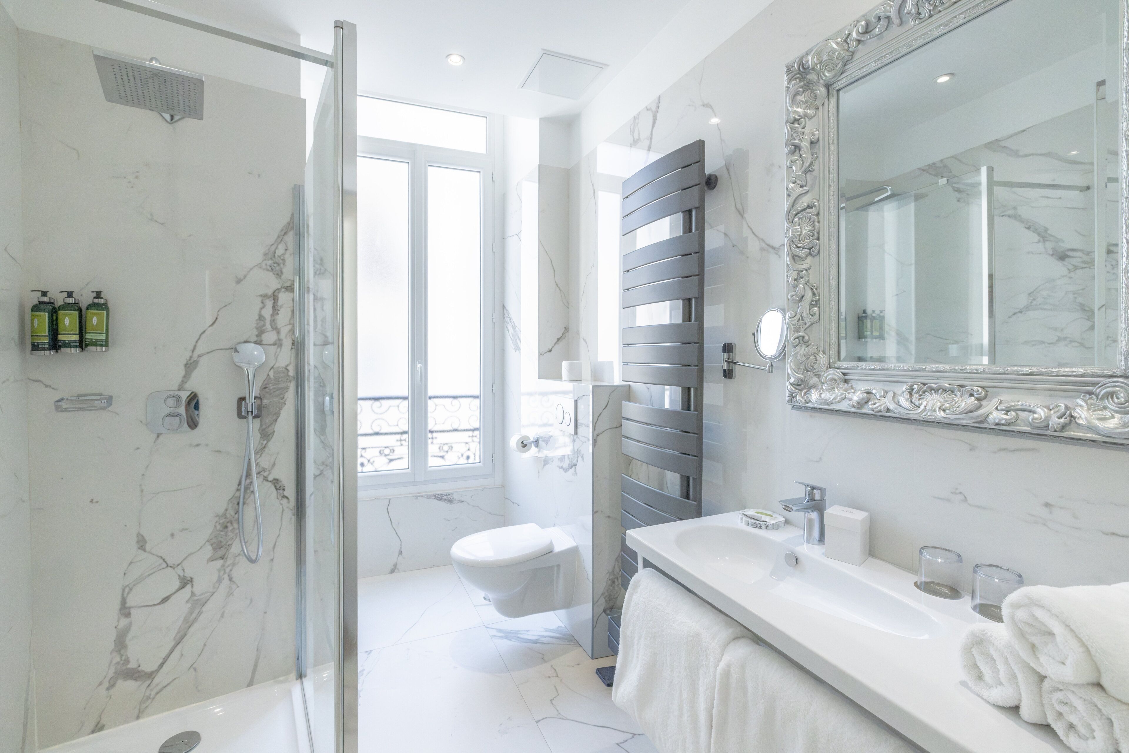Ein modernes Badezimmer mit Glasdusche, weißer Toilette und Waschtisch mit großem Spiegel.