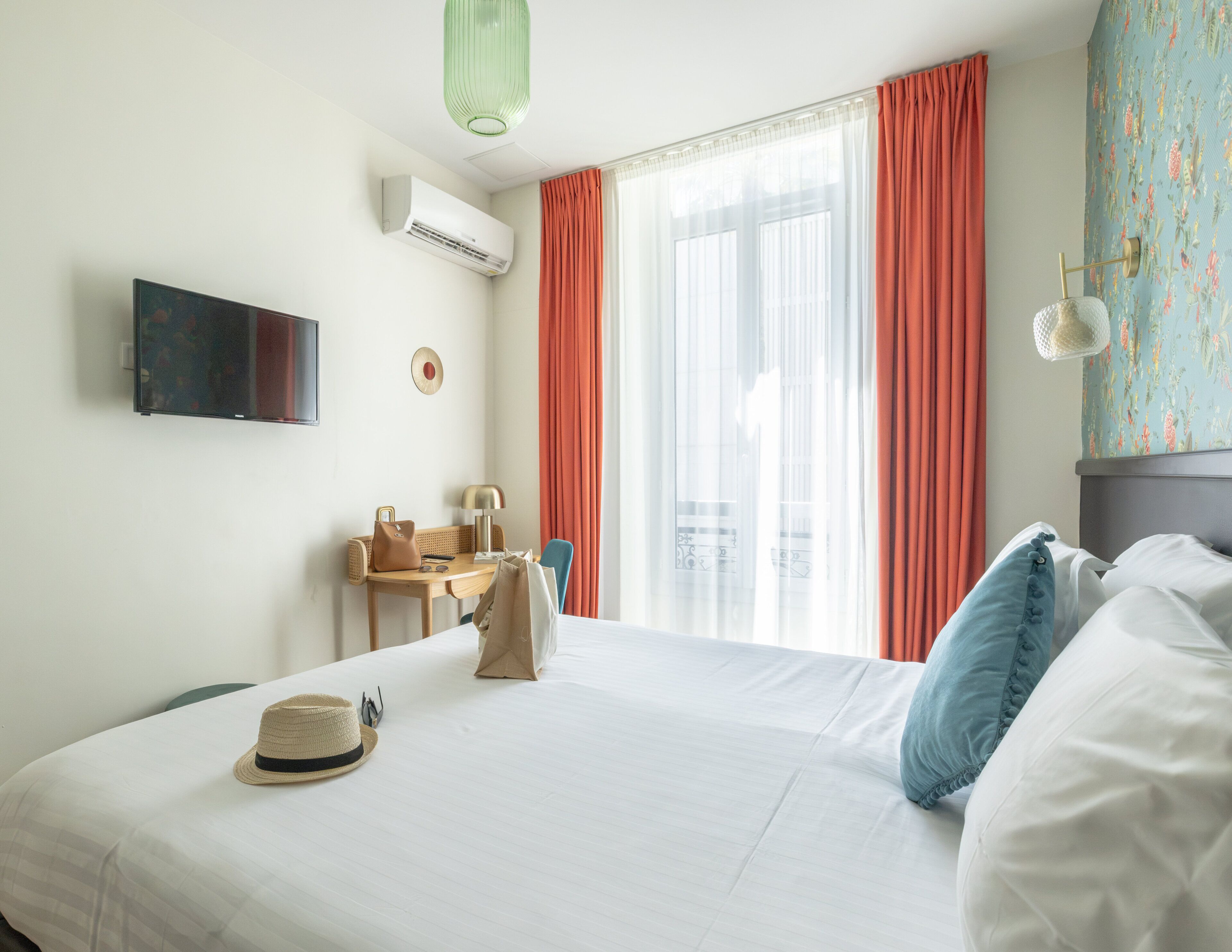 A hotel room with a bed, a desk, a chair, a television, and a window with curtains.