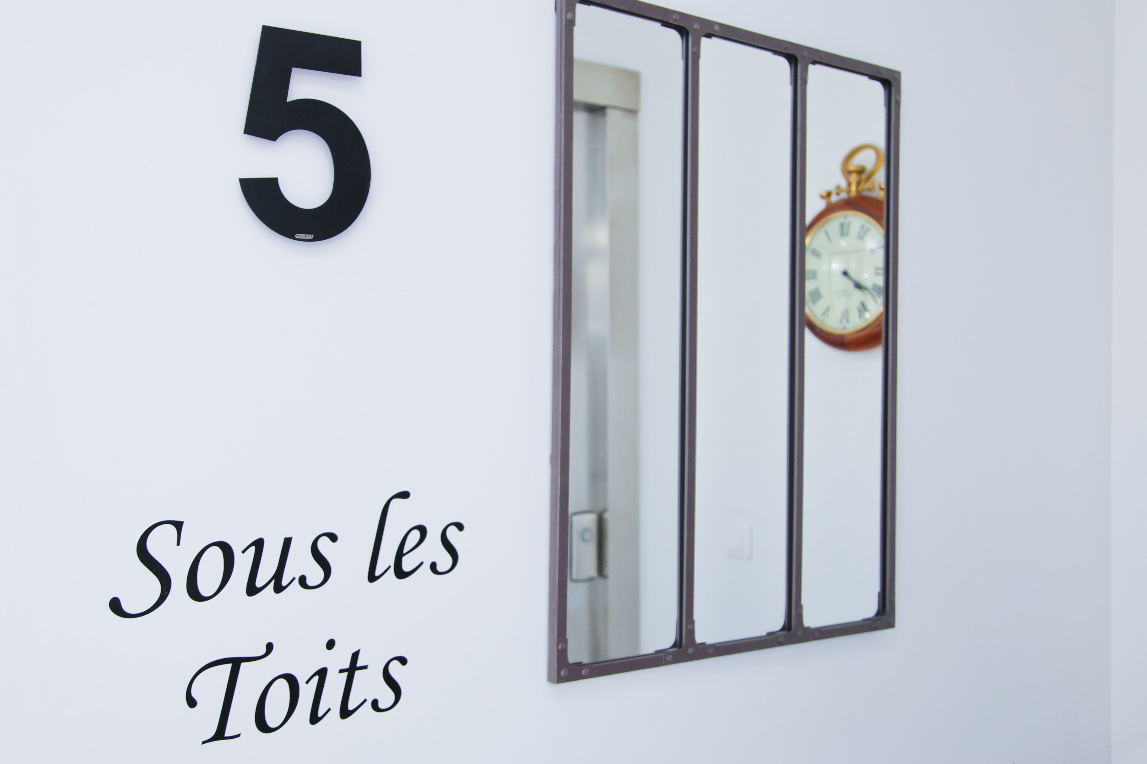 Seinä, jossa on suuri numero 5 ja teksti: »Sous les Toits».