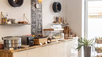 Een keukentafel met een koffieapparaat, een pan en verschillende soorten etenswaren.
