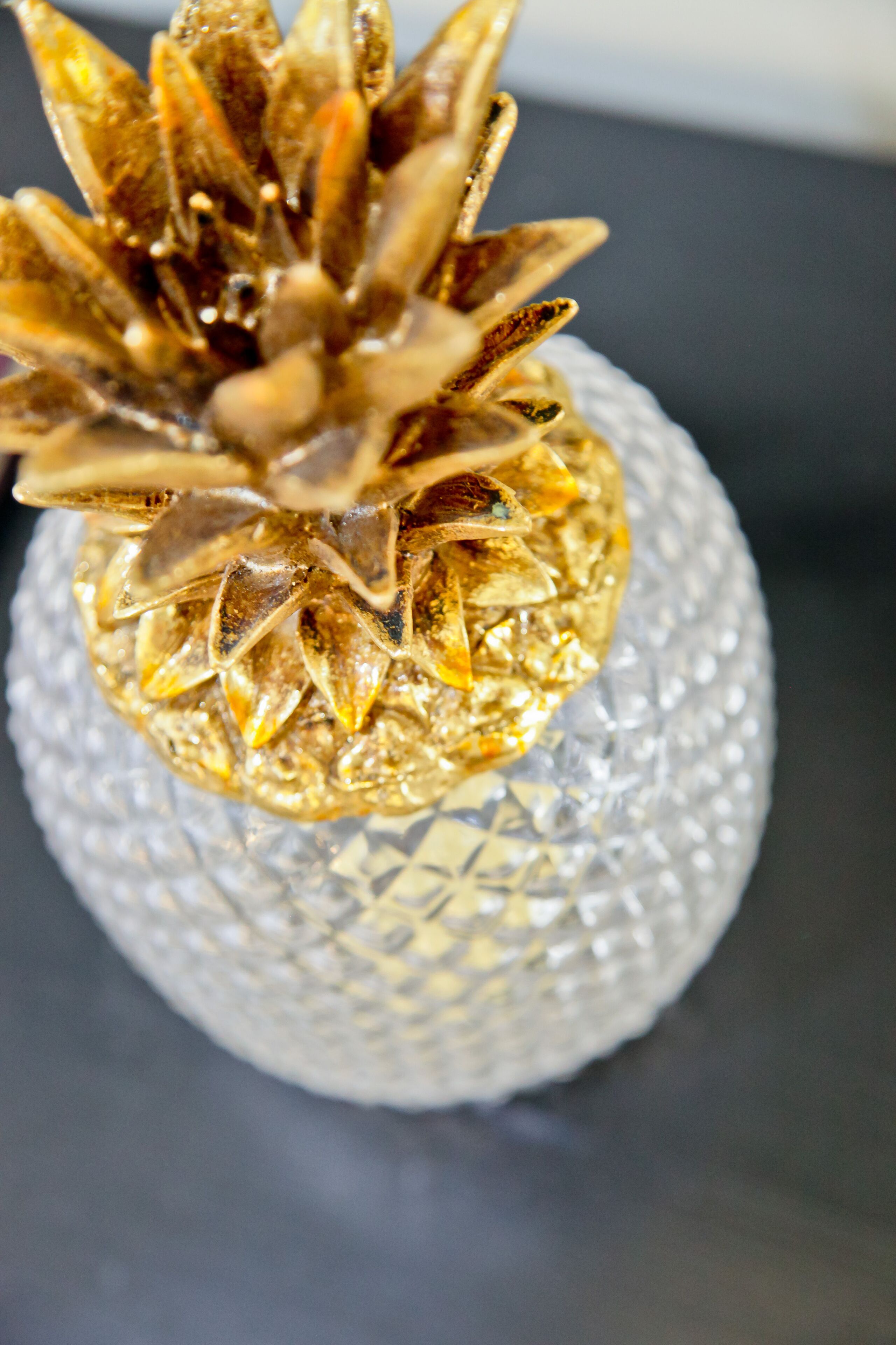A close-up of a decorative pineapple ornament on a textured glass surface.