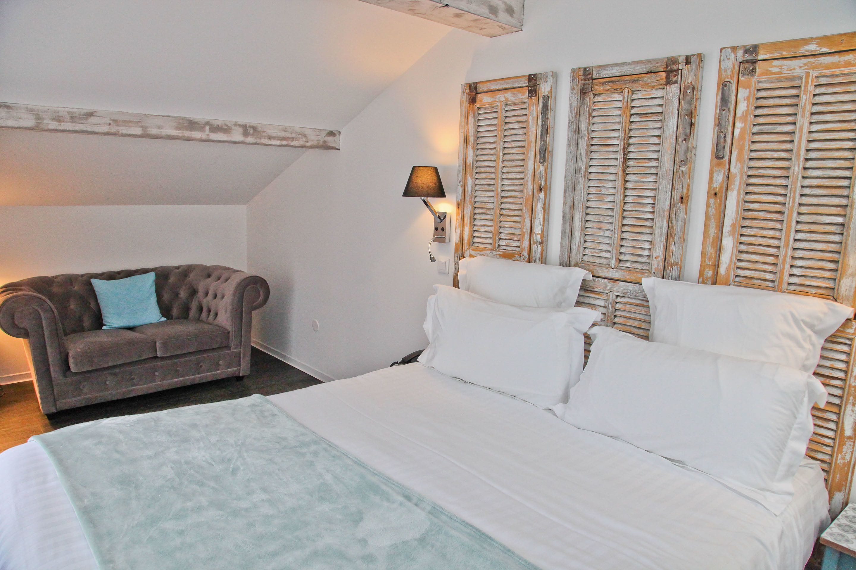 Une chambre à coucher avec un lit, un canapé et une lampe fixée au mur.