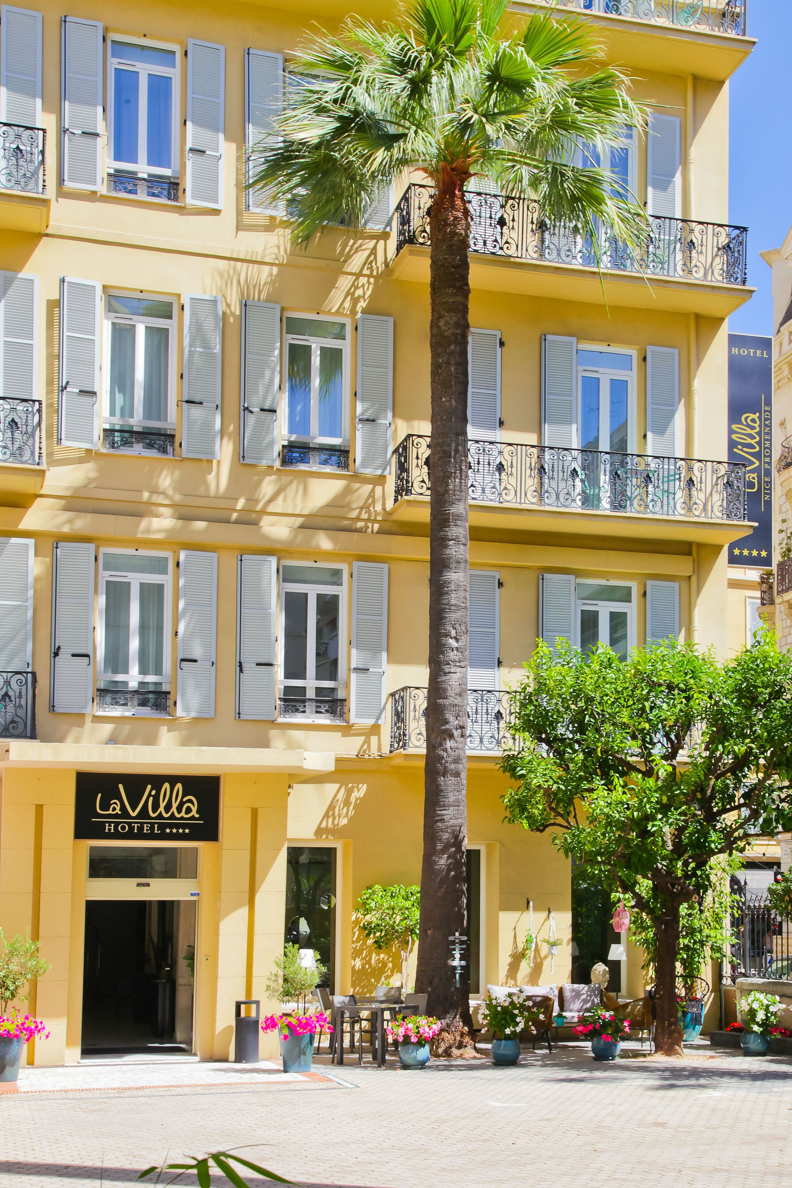 Un edificio amarillo con balcones y una palmera frente a él.