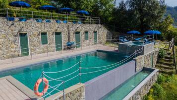 Relax by the serene pool surrounded by lush greenery and lounge chairs.
