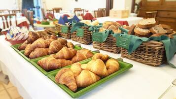 Un bufé con diferentes tipos de pan y bollería, incluyendo croissants y brioche.