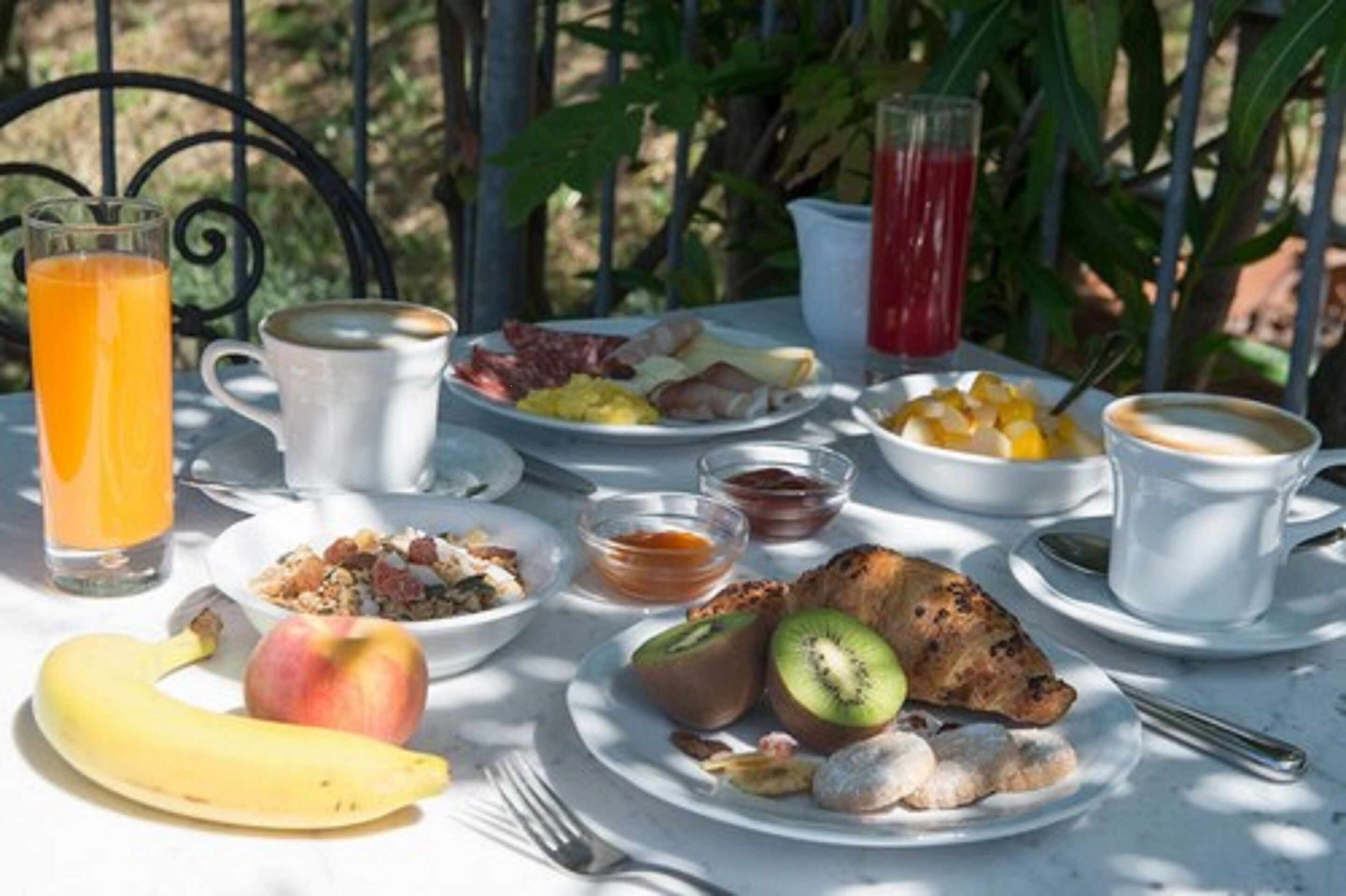 Uma mesa posta para o café da manhã, com diversos alimentos, bebidas e utensílios.
