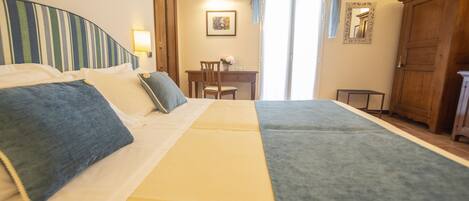 Una habitación de hotel con dos camas, un escritorio, una silla y un armario.