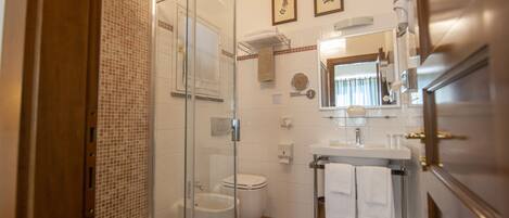 Un baño moderno con cabina de ducha de vidrio, inodoro y lavamanos con espejo.