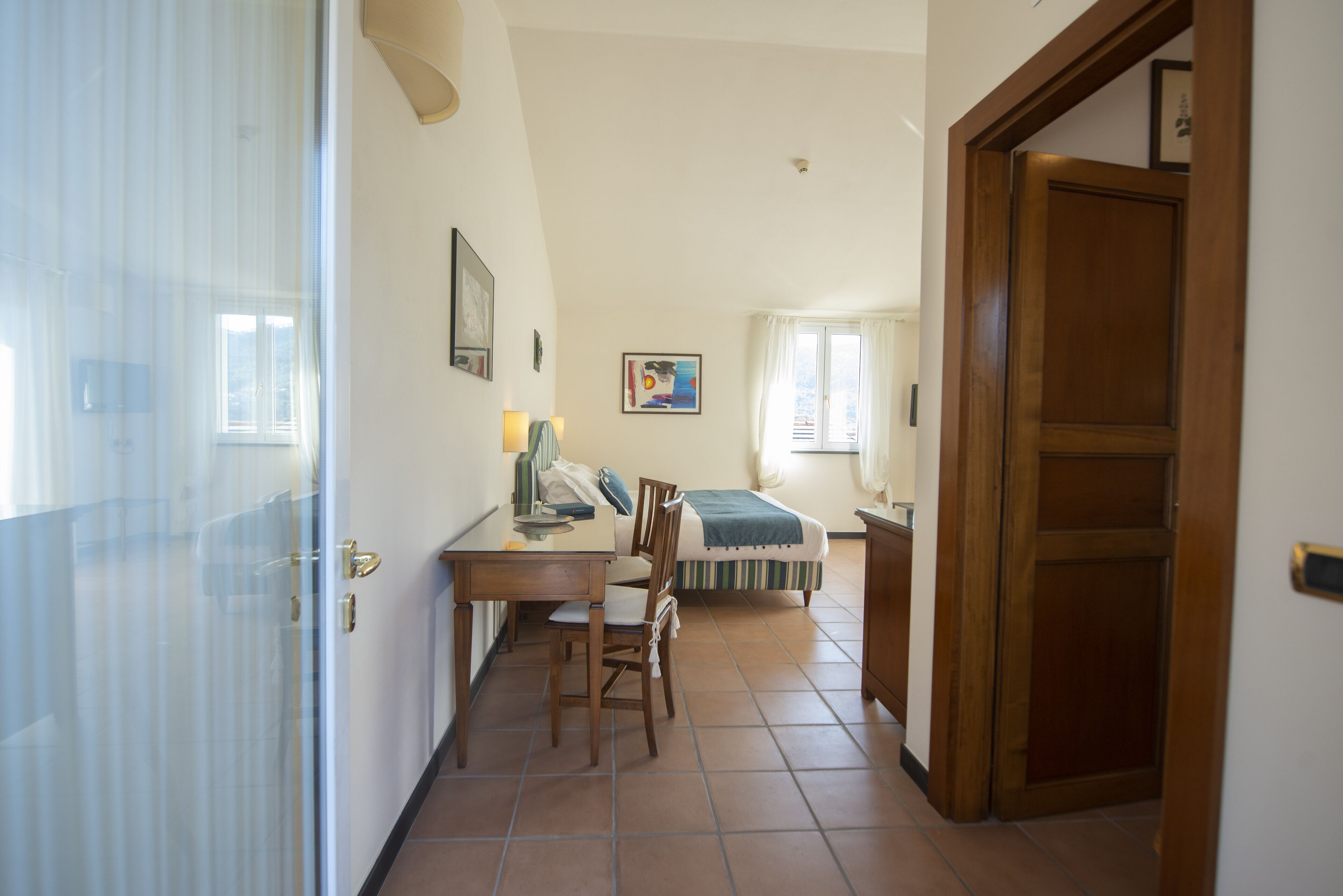 A narrow hallway with a bed, a desk, and a chair.