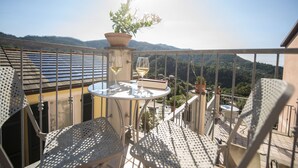 Un balcón con mesa, sillas, una planta en maceta y vistas a las montañas.