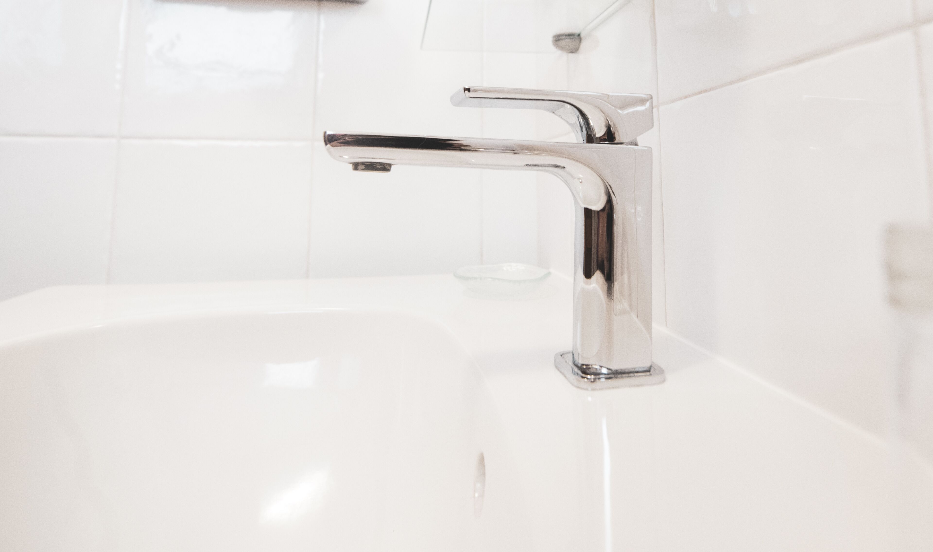 A modern bathroom with a chrome faucet and a white sink.