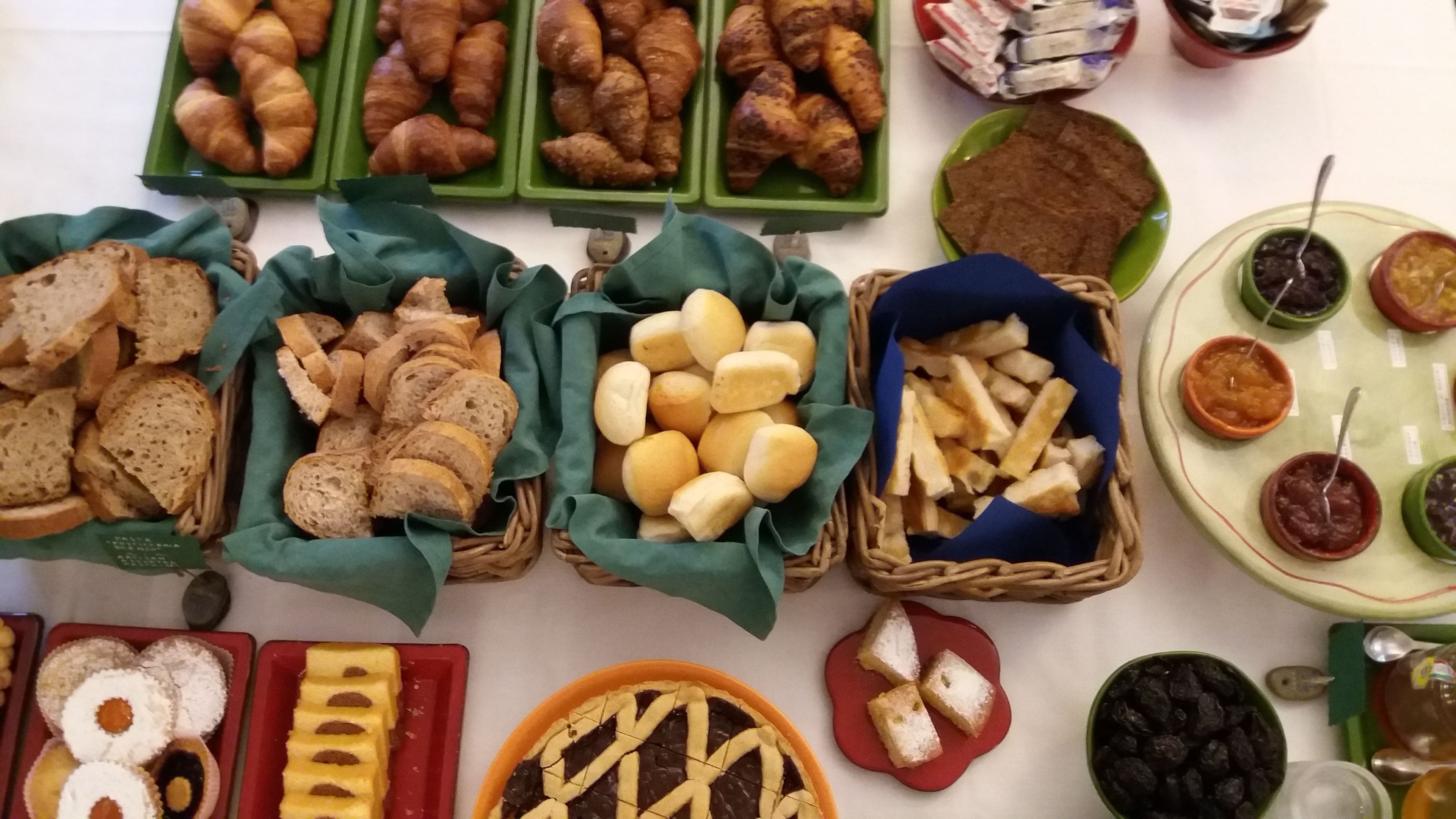 A variety of food items displayed in baskets and plates, including bread, pastries, and dips.